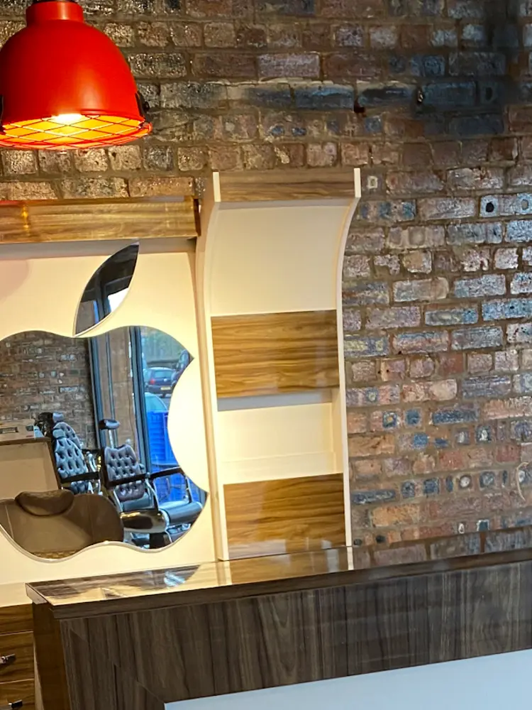 Apple-shaped mirror against an exposed brick wall under a red pendant lamp