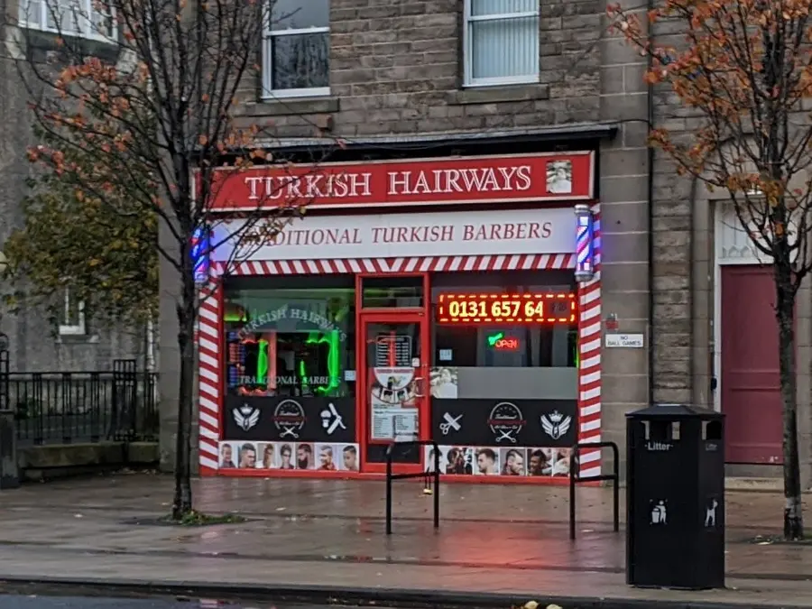 Turkish Hairways shopfront with red and white barber stripes and twin barber poles